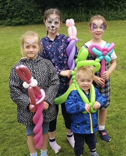 Group of children with their faces painted holding balloon animals in Telford